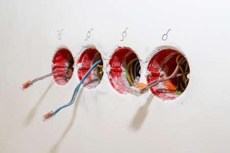 Electric cables sticking out of an orange box placed in the wall of the house in the room, cables connected with an electric connector.の写真素材