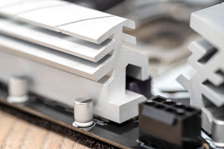 Macro shot of a silver heat sink dissipating heat from the power section on the motherboard of a...
