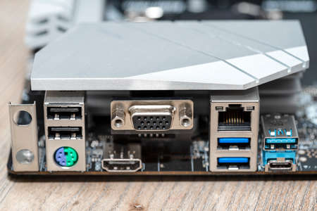 The rear panel of a desktop computer motherboard with visible connectors, USB, VGA, PS2 and RJ45...