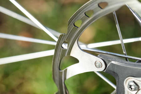 A macro shot of the front bicycle brake disc, visible spokes and a green background.