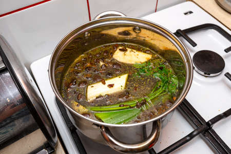 Mushroom soup with vegetables boiled in a metal pot on a gas stove.