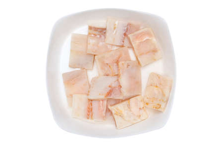 A fresh cod fish fillet cut into squares lying on a white plate, isolated on a white backgroundの写真素材