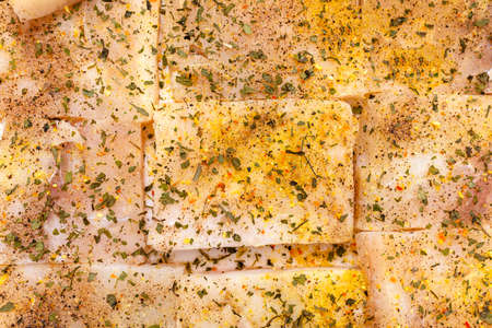Background made of cod fish fillet cut into squares and sprinkled with spices, top view.の写真素材