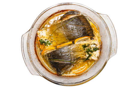 Baked pieces of carp in a glass bowl with melted butter, parsley and lemon slices, isolated on a white background , top view.の写真素材