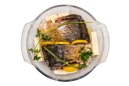 Pieces of raw carp arranged in a glass bowl with butter, parsley and lemon slices, isolated on a white background with, top view.の写真素材