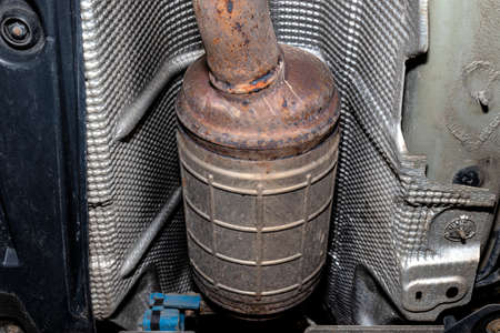 A diesel particulate filter in the exhaust system in a car on a lift in a car workshop, seen from below.の写真素材