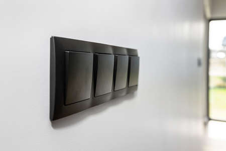 Black frame with a four-button light switch on the gray wall of the house.