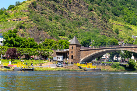 Cochem, Germany, June 13, 2021. People walking on the bridge and the sidewalk along the river in the...