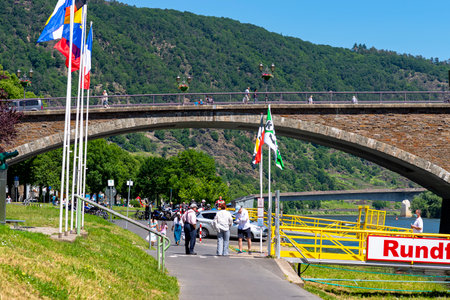 Cochem, Germany, June 13, 2021. People walking on the bridge and the sidewalk along the river in the tourist town of Cochem on the Moselle in Rhineland-Palatinate, Germany.のeditorial素材