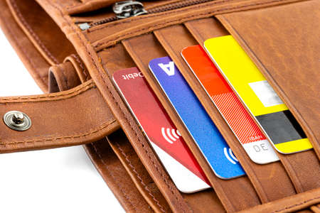 Macro photo of a brown mens leather wallet with debit and credit cards inside, isolated on a white...