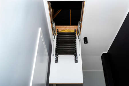 Folding metal stairs to the attic in the ceiling, open hatch and complex stairs, modern look.の写真素材