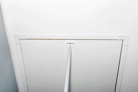 Folding metal stairs to the attic in the ceiling, closed hatch with a tube for opening, modern look.の写真素材