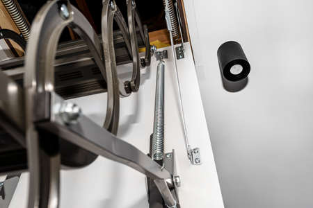 A spring tensioning mechanism that helps in opening a metal ladder to the attic placed in the...