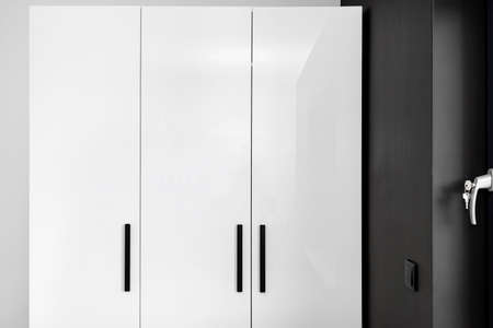 Large and high wardrobe in the bedroom with white fronts and black handles.の写真素材