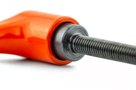 Macro photo of an orange clamping lever with black thread, isolated on a white background.