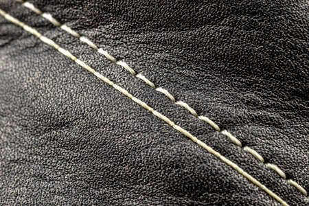 Macro background made of black natural leather with white stitching in the center.の写真素材