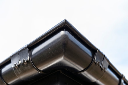 A metal, black gutter on a roof covered with ceramic tiles, visible corner of the gutter.の写真素材