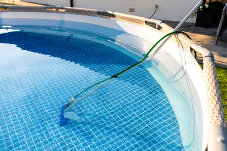 Cleaning the home pool in the garden with a brush, dragging dirt from the bottom of the pool.の写真素材