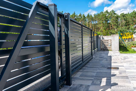 Modern panel fencing in anthracite color, visible sliding gate to the garage as well as a handle and...