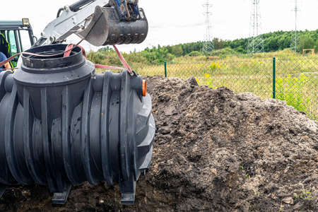 Installation of a single-chamber home sewage treatment plant, the excavator raises the tank.