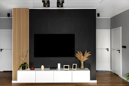 Black matte TV wall in the living room with a hanging TV set over a white wall unit.の写真素材