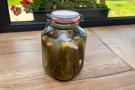 Pickled cucumbers with horseradish and garlic in a large glass jar, a traditional Polish dish.の写真素材