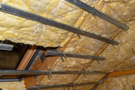 Aluminum frame with hangers placed on beams in the attic for mounting plasterboards, visible roof window.の素材 [FY310197824726]