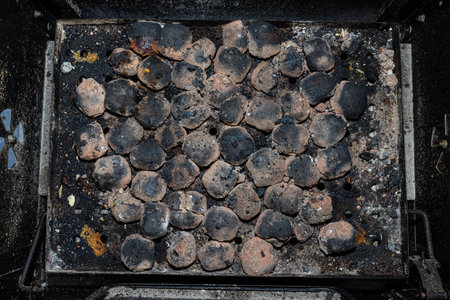 Cleaning a dirty grill while standing on the terrace and emptying the ashes.の写真素材