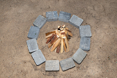 Prepared chopped pieces of wood to make a fire in a stone circle on the sand.の写真素材