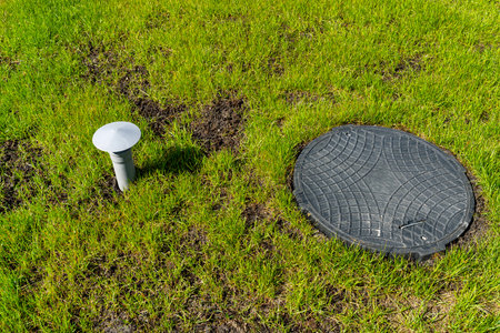 Hatch and vent from a household septic tank with no outflow placed in the garden.