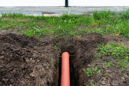 Orange PVC pipe buried in the ground connected to the gutter, used to connect to the drainage pipe.の写真素材