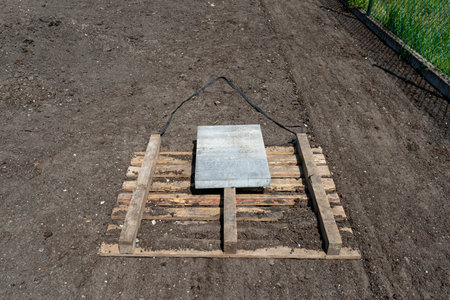 Leveling the chernozem in the yard with a pallet weighted with a concrete cube, preparing for sowing the lawn.の写真素材