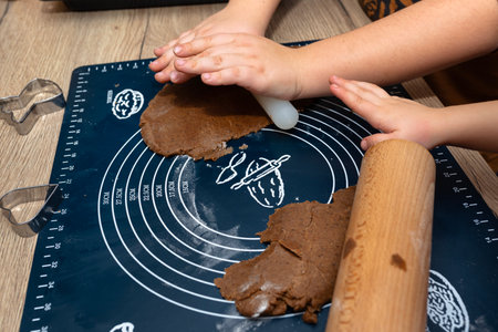 Children make gingerbread dough using a wooden and plastic rolling pin.
