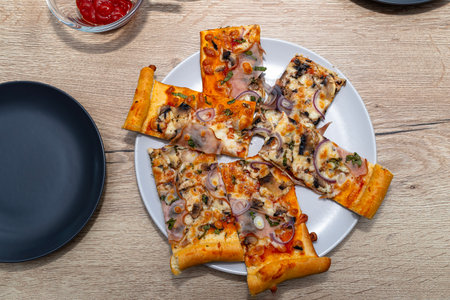 Baked homemade pizza lying on a plate on the table, visible sauces in bowls.