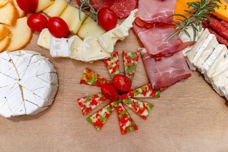 Various cheeses and cold cuts spread out on the table on baking paper, evening party at home, top view.の写真素材