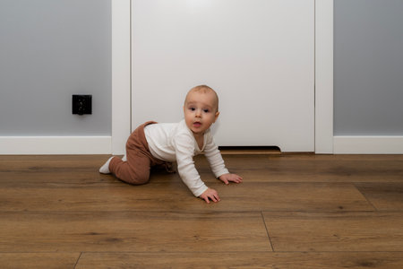 A seven-month-old baby touches a black electrical outlet on the wall.の写真素材