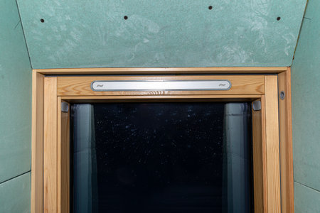 Roof window covered with blue plaster, visible vapor-permeable foil.