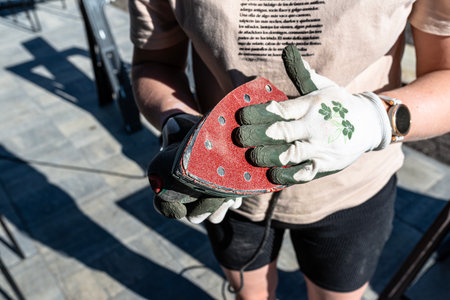 A woman replaces the red sandpaper in an orbital sander.