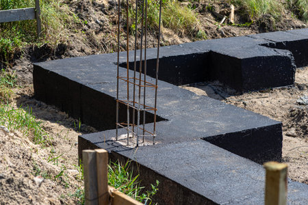 Wide foundation strips painted with black dispersion asphalt-rubber mass, visible reinforced...