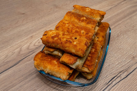 Fried croquettes filling a glass dish on a wooden table, offering a traditional snackの写真素材