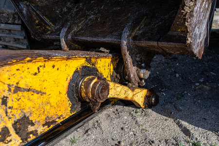 Close up of a long reach excavator arm, bucket, and hydraulic cylinder covered in dirt
