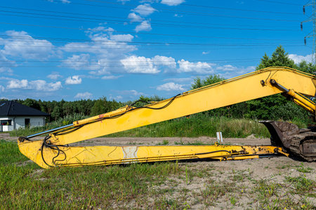Yellow heavy equipment excavator long arm for deep excavation resting on ground