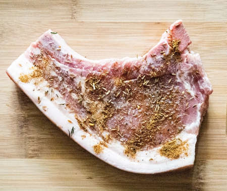 Raw pork ribs with spices and herbs on a wooden cutting board.の写真素材