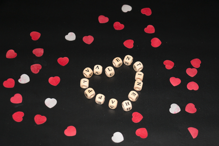 Heart made with white cubes with black letters on a black background with some red and white hearts aroundの写真素材