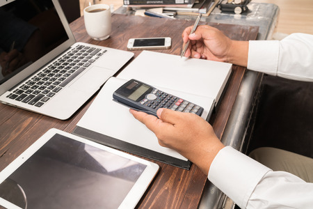 man working with calculator, business document and laptop computer notebookの写真素材