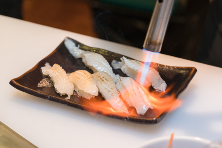 chef using a torch burn on sushi in the kitchenの写真素材