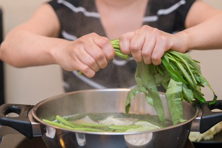 Woman puts vegetables into the pot. Conception of healthy food preparing.の写真素材