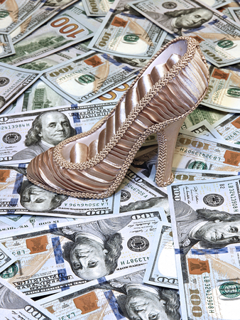 Women's shoe on a background of plurality of US dollars bills