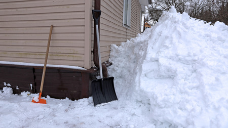 Clearing large drifts of snow shovel near the house