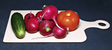 Fresh vegetables for salad on a cutting board on a dark backgroundの写真素材